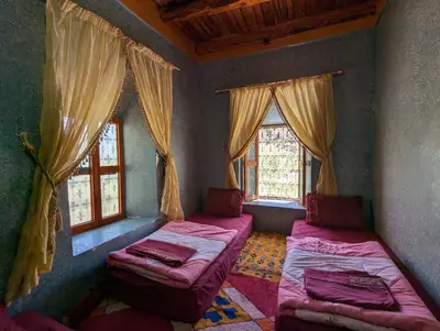 two beds in a room with two windows at Gite D'etape Ait Ali Nito Assounfou in Megdaz