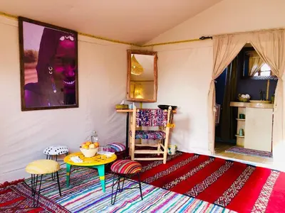 a room with a table and chairs and a rug at Pueblo Touareg - Private Tents in Merzouga