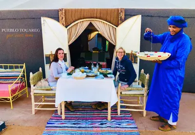 a group of people sitting around a table in a room at Pueblo Touareg - Private Tents in Merzouga