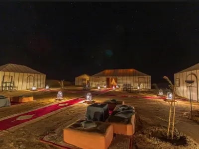 a group of buildings at night with lights at Expedition Luxury camp in Merzouga