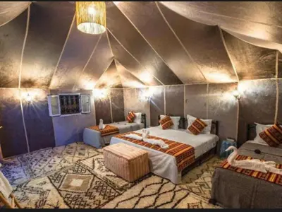 a bedroom with two beds in a room with a ceiling at Expedition Luxury camp in Merzouga