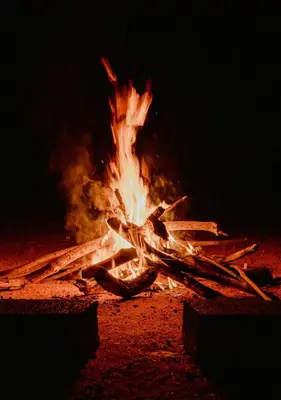 a fire is burning in the sand at night at Expedition Luxury camp in Merzouga