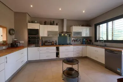 a kitchen with white cabinets and a stool in it at Magnifique Villa dans domaine prive in Douar Soukkane