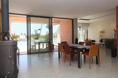a dining room with a table and some chairs at Magnifique Villa dans domaine prive in Douar Soukkane
