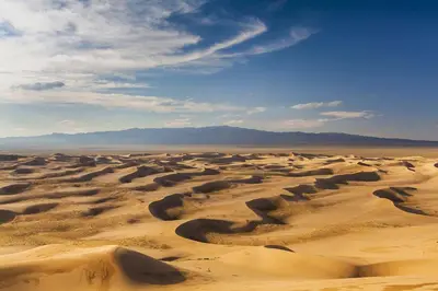 a desert with sand dunes and mountains in the background at Erg chagaga in Mhamid