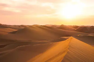 a desert with the sun rising over the sand dunes at Erg chagaga in Mhamid