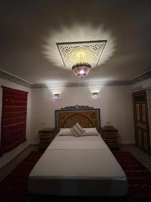 a bedroom with a large bed and a chandelier at Dar Moulin in Fès