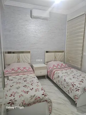 a bedroom with two beds and a white wall at Appartement bassatine in Fès