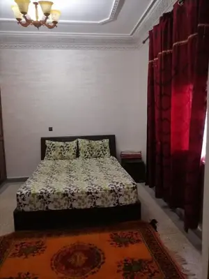 a bedroom with a bed and red curtains and a rug at Big flat in ouarzazate city, Morocco in Ouarzazate