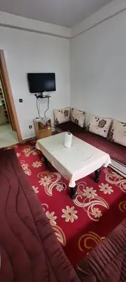 a living room with a table on a red rug at Apparemment bien équipé in Beni Mellal