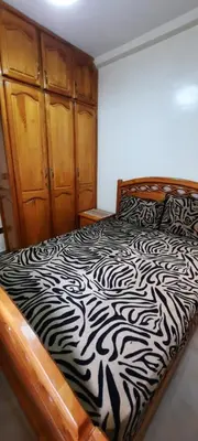 a bedroom with a black and white bed with wooden cabinets at Apparemment bien équipé in Beni Mellal
