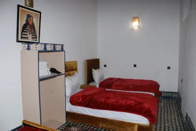 a bedroom with two beds with red sheets at Dar Fes Flower in Fès