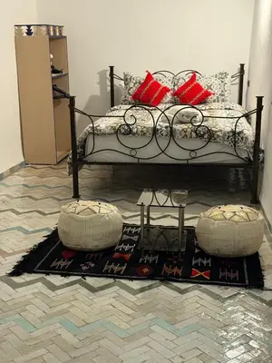 a bedroom with a bed with red pillows and a rug at Dar Fes Flower in Fès