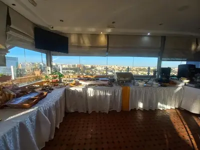 a large room with white tables with a view of a city at Hotel Swani in Meknès