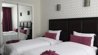 a hotel room with two beds and a mirror at Hotel Swani in Meknès