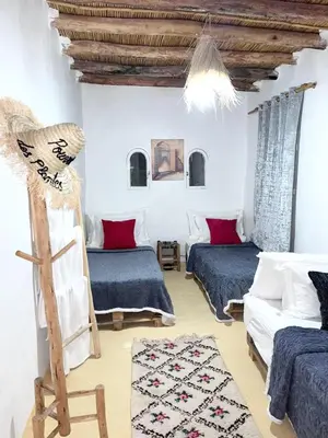 a room with two beds and a chair in it at Ferme d'hôtes Pouvoir des Plantes in Ourika