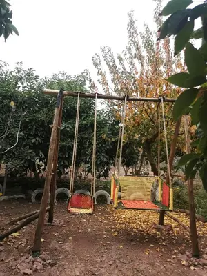 a swing in a park with two chairs on it at Ferme d'hôtes Pouvoir des Plantes in Ourika