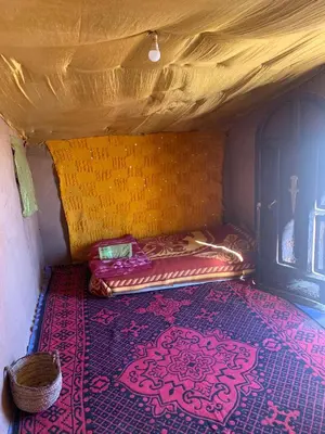 a small bed in a room with a rug at Hammadi Camp in Mhamid