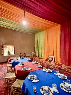 a group of four tables in a room with curtains at Hammadi Camp in Mhamid