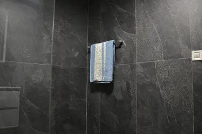 a black tiled bathroom with a towel on a wall at Bloemenhuis 2 - Centre-ville Fez in Fès