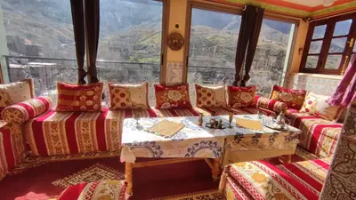 a living room with a table and a large window at Dar agzwal in Tacheddirt