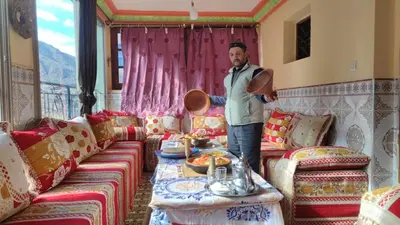 a man standing in a living room with a table at Dar agzwal in Tacheddirt