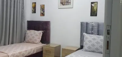 a bedroom with two beds and pictures on the wall at Guercif in Guercif