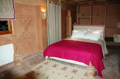 a bedroom with a large bed with a red blanket at Kasbah Alami in Kalaat MGouna