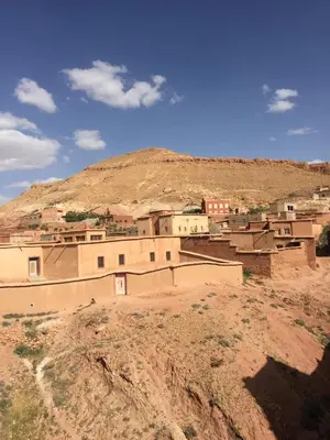a village in the desert with a hill in the background at Kasbah Alami in Kalaat MGouna