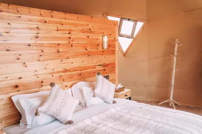a bedroom with a wooden wall and a bed at Antares Desert Camp in Merzouga