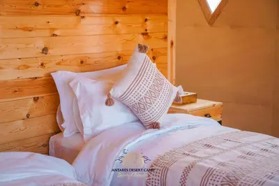 a bedroom with a bed with a wooden wall at Antares Desert Camp in Merzouga