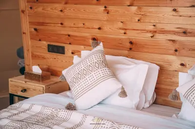 a bed with white pillows and a wooden headboard at Antares Desert Camp in Merzouga