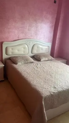 a bedroom with a white bed with a pink wall at Très bel Apt Fès,3 ch dans un quartier trop chic bien placé in Fès