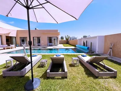 a pool with chairs and an umbrella in a yard at villa Elyssa !Confort & modern avec Piscine privée in Marrakech