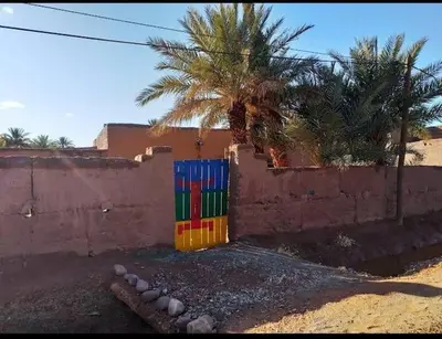 a colorful fence in front of a house with a palm tree at Dar itran in Mhamid