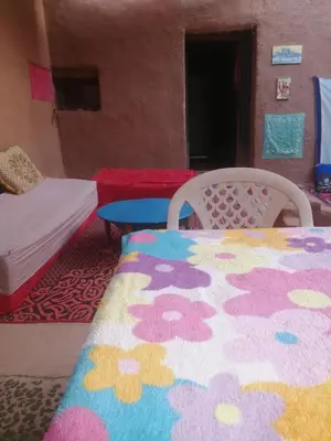 a bedroom with a bed and a table and a rug at Dar itran in Mhamid