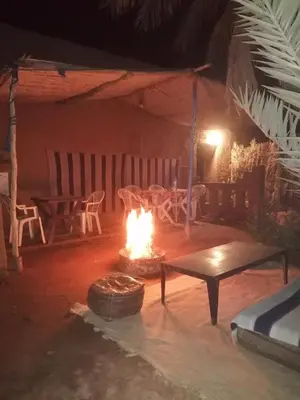 a fire pit in a room with a table and a bench at Dar itran in Mhamid