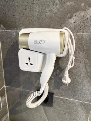 a white electric hair dryer sitting on a wall at Studio plein centre-ville ! in Fès