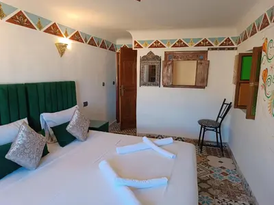 a bedroom with a white bed and a chair at Riad Amira Fes in Fès