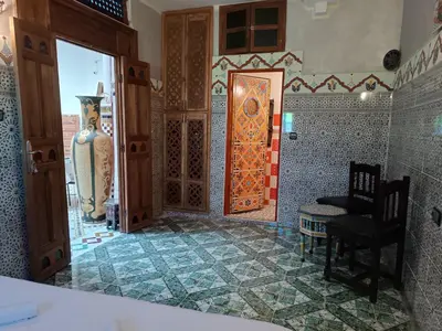 a bathroom with a door and a chair and a table at Riad Amira Fes in Fès