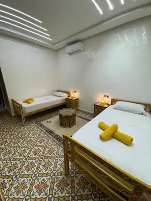 a room with two beds and two tables at Appartement Dar LALA 2 in Fès