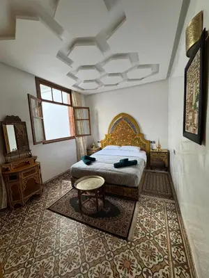 a bedroom with a bed and a table in it at Appartement Dar LALA 2 in Fès