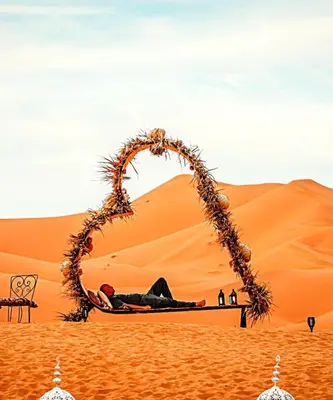 a man laying on a bed in the desert at Fabulos Merzouga Luxury Camp in Hassilabied