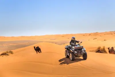 a man riding a motorcycle in the desert with a dog at Fabulos Merzouga Luxury Camp in Hassilabied