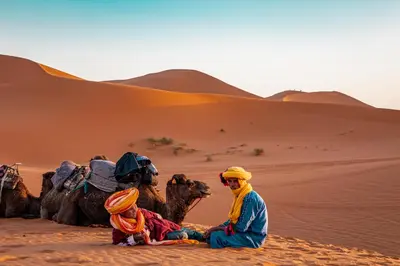 a group of people sitting in the desert with their camels at Fabulos Merzouga Luxury Camp in Hassilabied