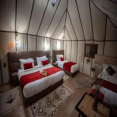 a bedroom with two beds in a tent at Golden Sahara camp in Merzouga