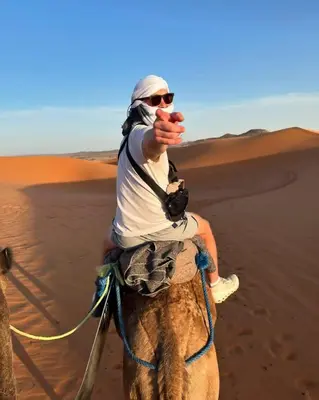 a man riding a camel in the desert at Golden Sahara camp in Merzouga