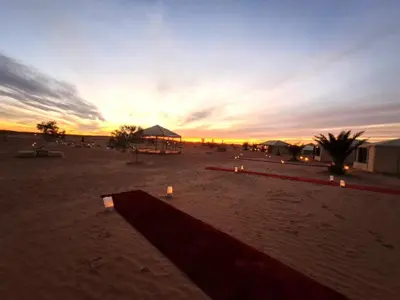 a sunset in the desert with candles in the sand at Golden Sahara camp in Merzouga