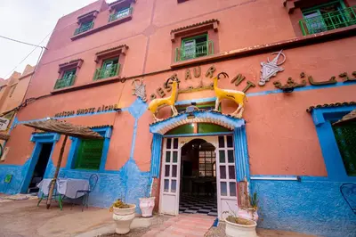 a pink and blue building with a sign on it at hotel dar aicha in Tinerhir