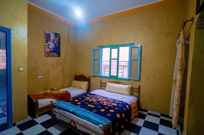 a bedroom with two beds and a window at hotel dar aicha in Tinerhir